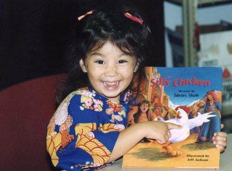 Little girl pointing at the cover of The Silly Chicken