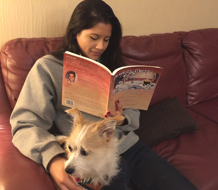 Girl reading the book Me and My Memory with a dog on her lap